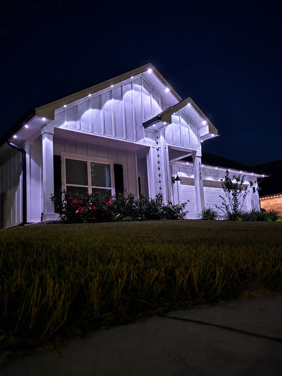 Two-story farmhouse outlined in bright white permanent lighting