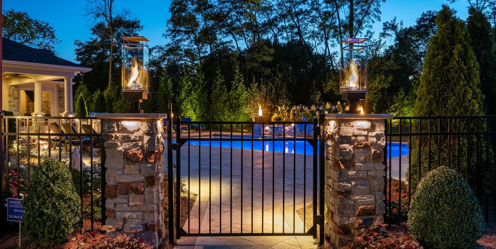 Warm white lighting on a stone entry gate and pillars
